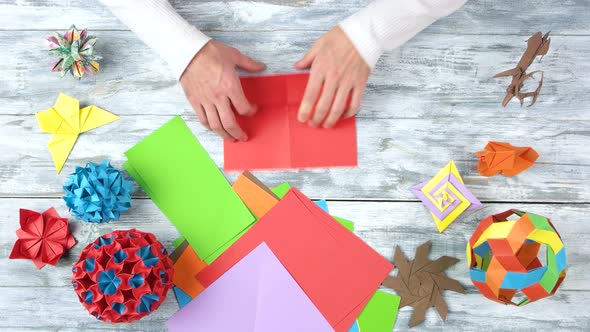 Person Folding Red Paper Sheet.