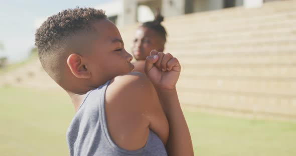 Video of focused african american boys stretching outdoors on sunny day