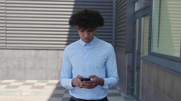 Young Attractive Man Walking in the Town While Using His Mobile Phone