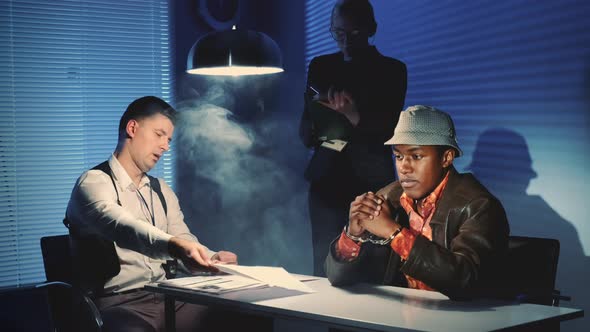 Medium Shot of Black Prisoner in Handcuffs Having Interview with Caucasian Detective in