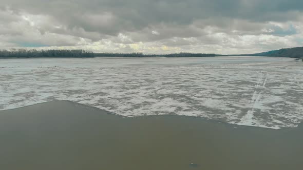 Deep Grey River Water with White Ice Against Dense Forests