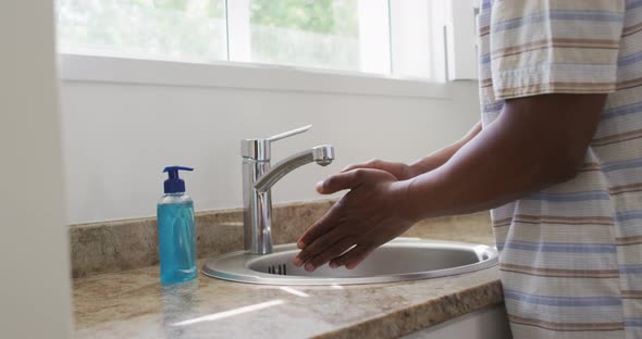 Mid section of man washing his hands in the sink