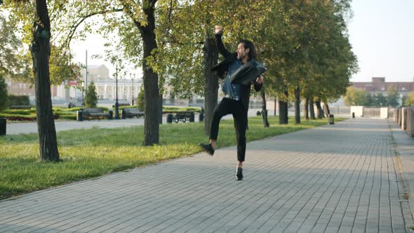 Successful Young Businessman Walking in City with Suitcase Then Jumping and Dancing