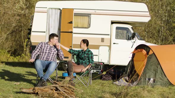 Hipster Boyfriend Kissing His Girlfriend Hand While Sitting on Camping Seats