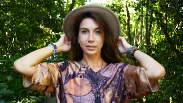 Portrait of a Young Brunette in a Hat Against the Backdrop of a Green Park