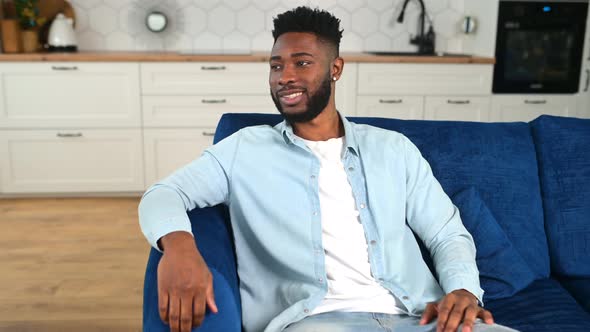 Serene AfricanAmerican Guy in Casual Wear Sitting on the Comfortable Sofa