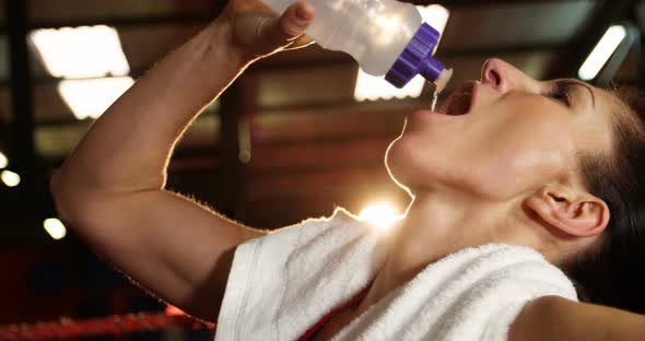 Female boxer drinking water in boxing ring