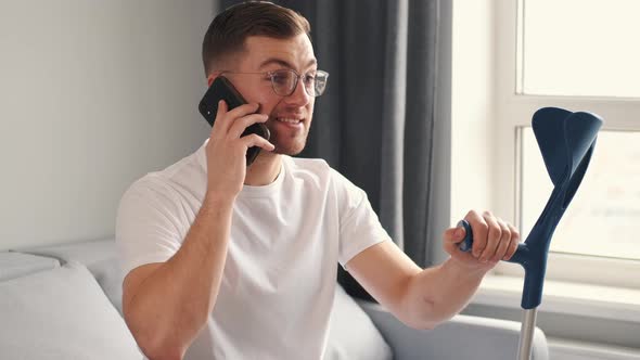 Young Man with Walking Stick Talk By Phone Indoors