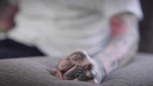 Closeup Couch Arm with Tattooed Male Fist Hitting Punching