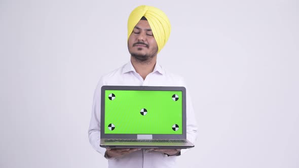 Happy Bearded Indian Sikh Businessman Thinking While Showing Laptop