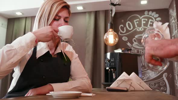 Female Waitress Drinks Coffee and Uses a Paper Napkin