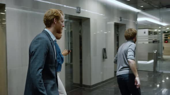 Business People Exiting Lift Car in Corridor