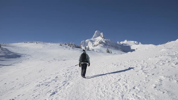 Person with Backpack Hiking in High Altitude Mountain Environment During Winter Season