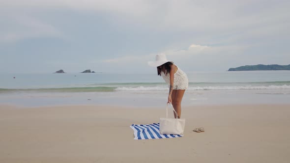 Woman In Sun Hat Arranging Bag And Beach Towel