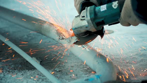 Worker on Winter Day Treats Metal Gates with Angle Grinder and Sparks Fly