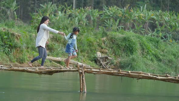 Mother And Her Daughter Walking Through River