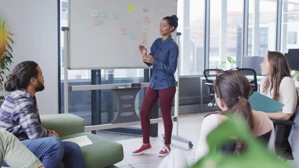 Diverse group of business colleagues brainstorming using whiteboard in meeting room