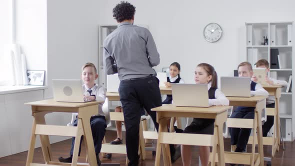 Enthusiastic Afro-American Man Teaching Computer Literacy at School