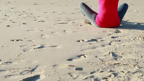 Senior woman doing yoga on the beach