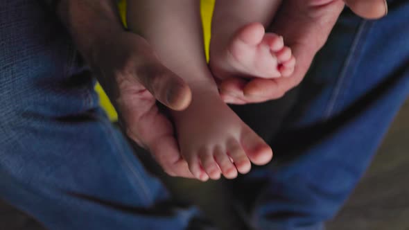 Close Up Grandpa Hands Holding Baby's Feet Playing with Newborn