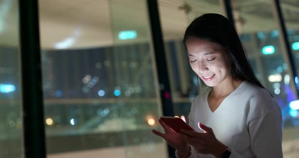 Woman look at mobile phone in city at night