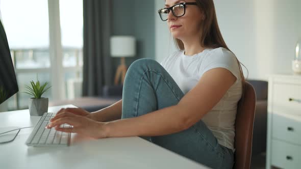 Casually Dressed Woman Working with a Computer at Home in a Cozy Environment