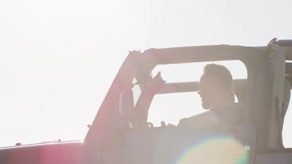 Happy caucasian gay male couple in car admiring the view and pointing on sunny day at the beach