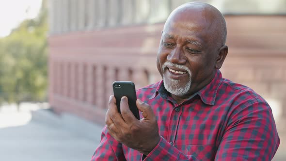 Overjoyed Senior Black Male Grandfather Waving Hand Making Video Call Looking at Smartphone Camera