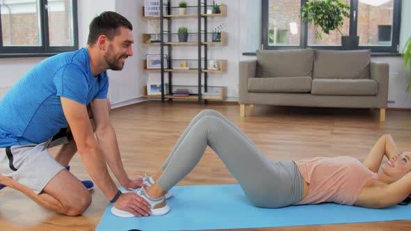 Woman with Personal Trainer Doing Sit Ups at Home