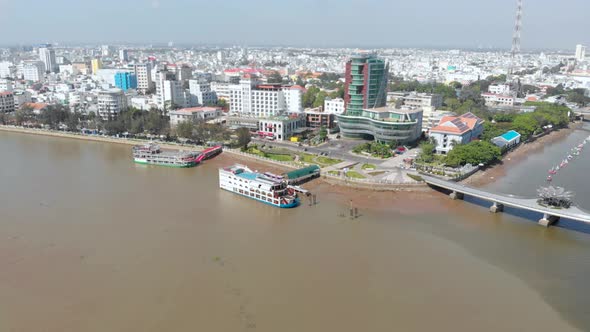 Aerial: Can Tho city skyline bridges over Mekong River, pedestrian walkaway waterfront skyscraper, M