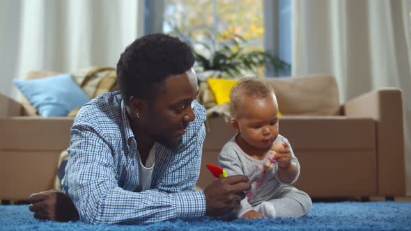 Happy African American Father and Baby Daughter Playing with Toys in Living Room