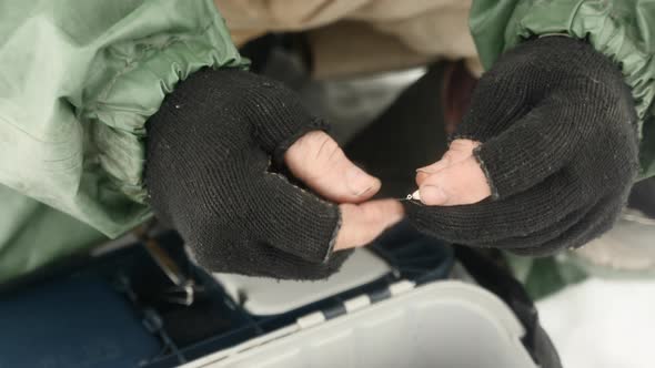 Fisherman with fishing rod and tackle is preparing for winter fishing