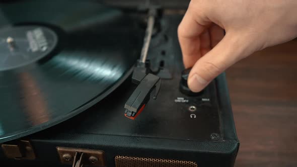 A close-up shot of a hand  turning on a turntable and placing the needle on the record.