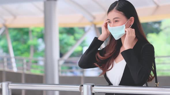 Portrait of business woman show action of wearing hygiene mask on the walk way in city