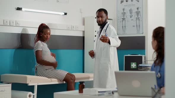 African American Doctor Giving Prescription Pills to Pregnant Patient