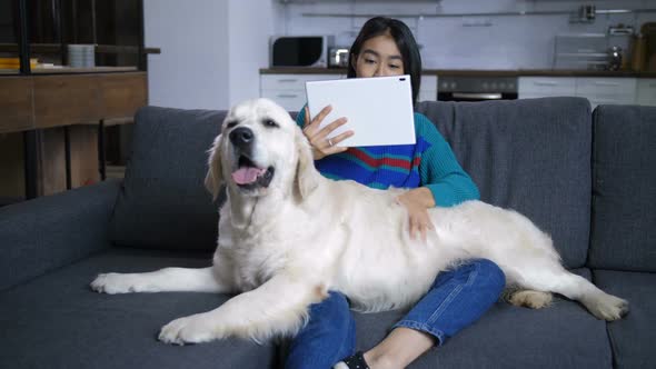 Young Hindu Woman Watching Tablet and Stroking Dog