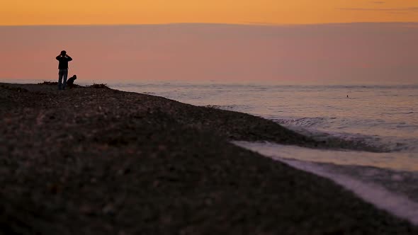 Mother and child enjoying view of peaceful sea, walking on the beach at sunset