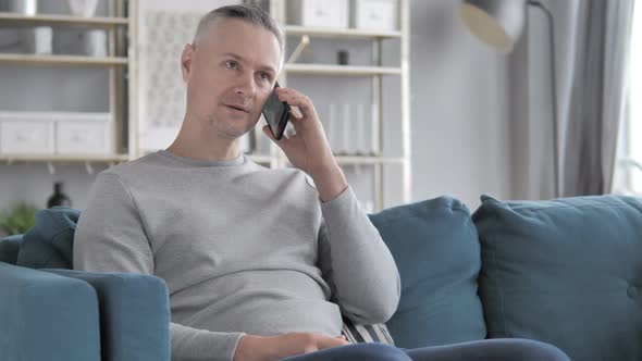 Gray Hair Man Talking on Phone While Sitting on Couch