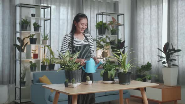 Smiling Asian Woman Holding Watering Pot To Water The Plants At Home