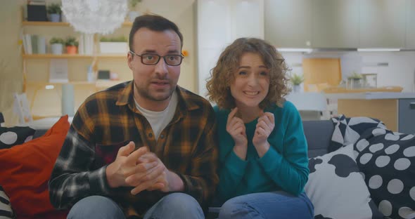 Happy Couple Watching Tv Sitting on Sofa at Home