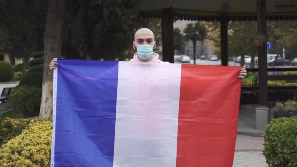 man with face mask holds France flag