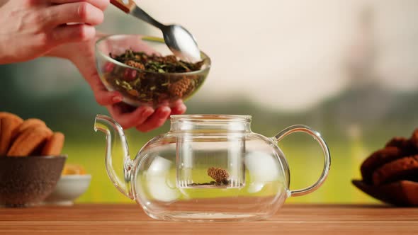 Putting Dry Tea Leaves Into Teapot on a Wooden Table