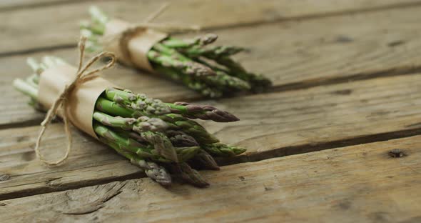 Video of two fresh asparagus bundles with copy space on wooden background