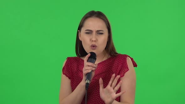 Portrait of Tender Girl in Red Dress Is Singing Into a Microphone and Moving To the Beat of Music