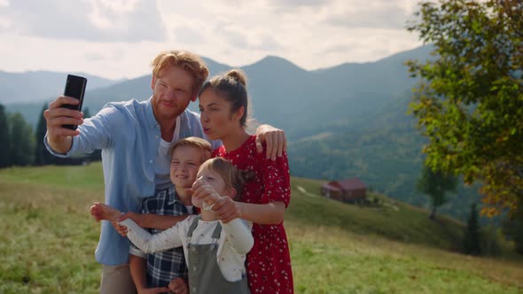 Joyful Family Taking Selfie with Sticking Tongues on Hill