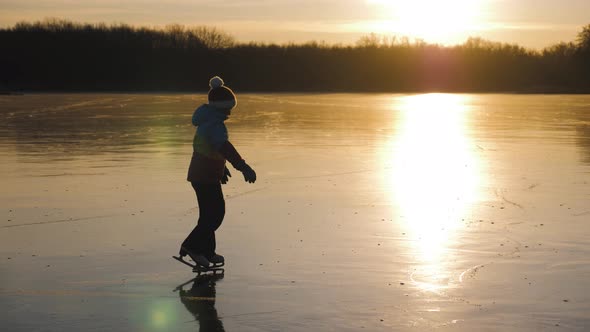 Cute Little Girl Is Going Skate Outdoors at Sunset. A Schoolgirl Enjoying Ice Skating at Frozen Lake