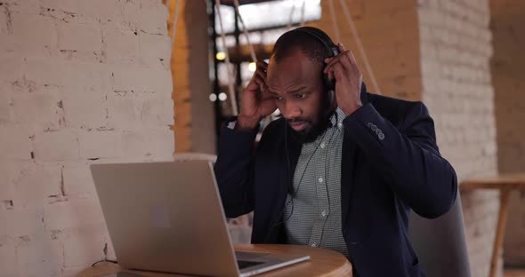 African Businessman Works By Laptop PC in Headphones