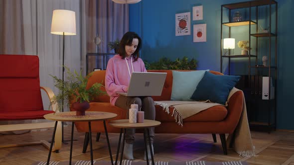 Young Adult Woman Sit on Couch Using Laptop Notebook Studying Shopping or Working Online at Home