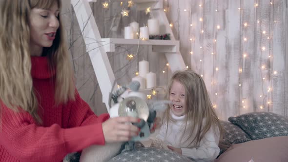 Fair Haired Mum Shows Snow Globe to Smiling Daughter