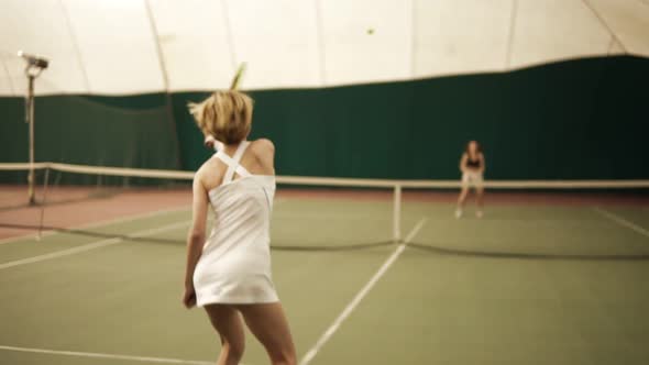 Muscular Blond Sportswoman Playing Tennis with an Unrecognizable Female on the Background Slowmotion